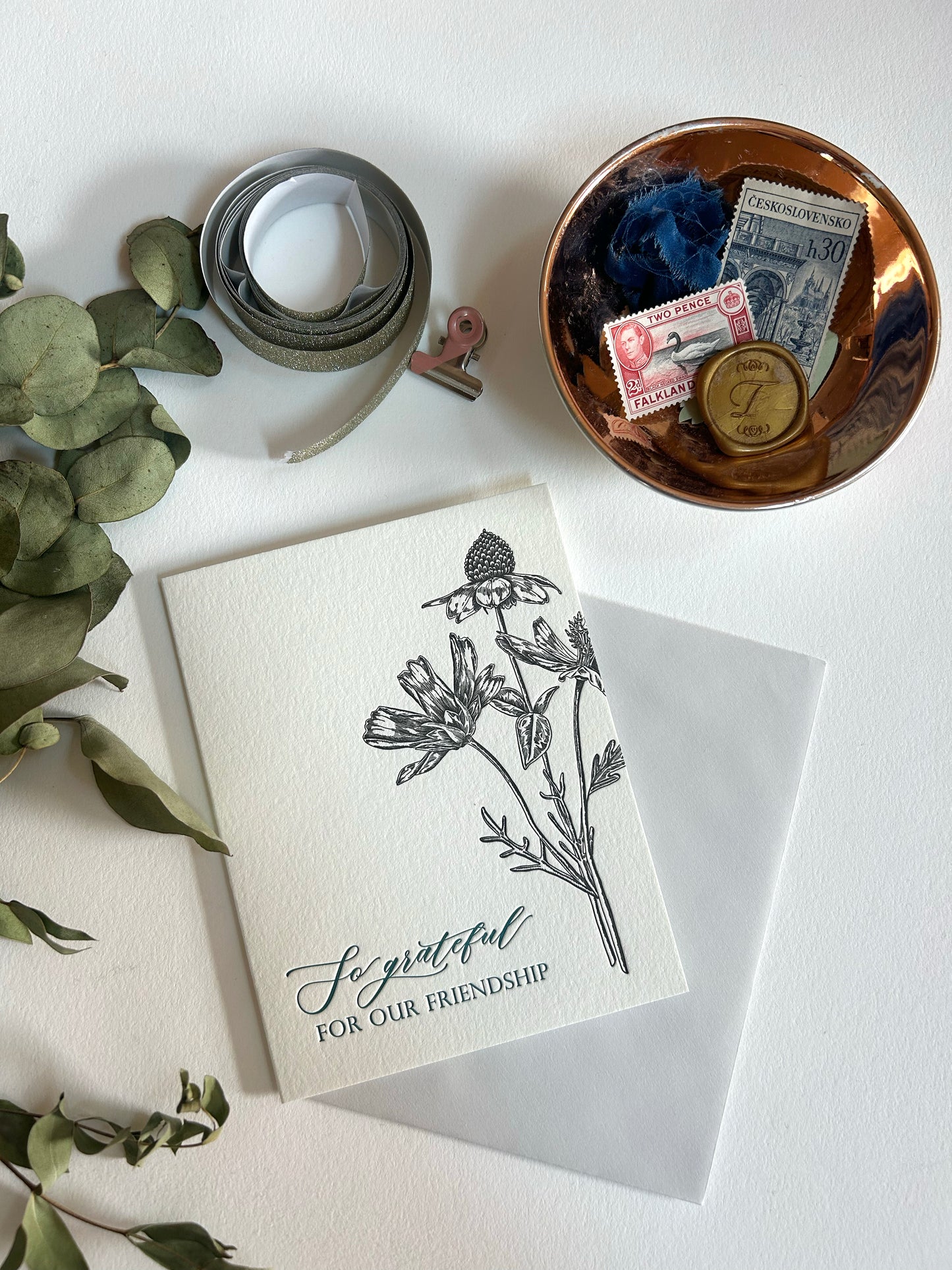 A style shot of Rust Belt Love's letterpress friendship card with black florals that reads "So grateful for our friendship"