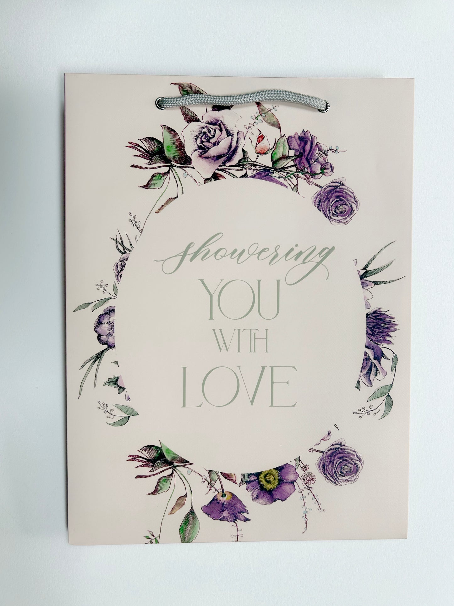 Flat pink floral gift bag that reads "Showering you with love" by Rust Belt Love