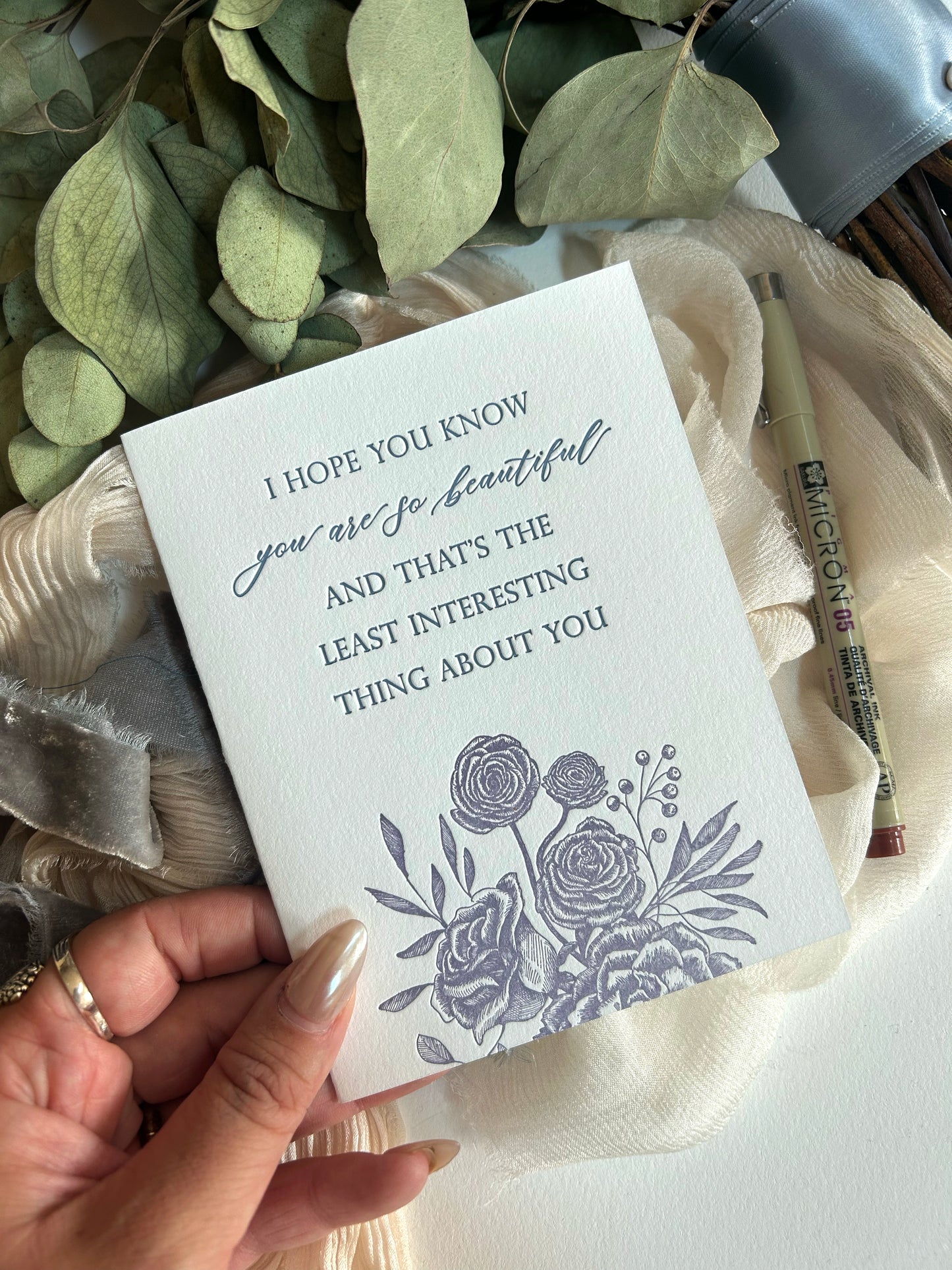 A style shot of Rust Belt Love's love letterpress floral greeting card that reads "i hope you know you are so beautiful and that's the least interesting thing about you"
