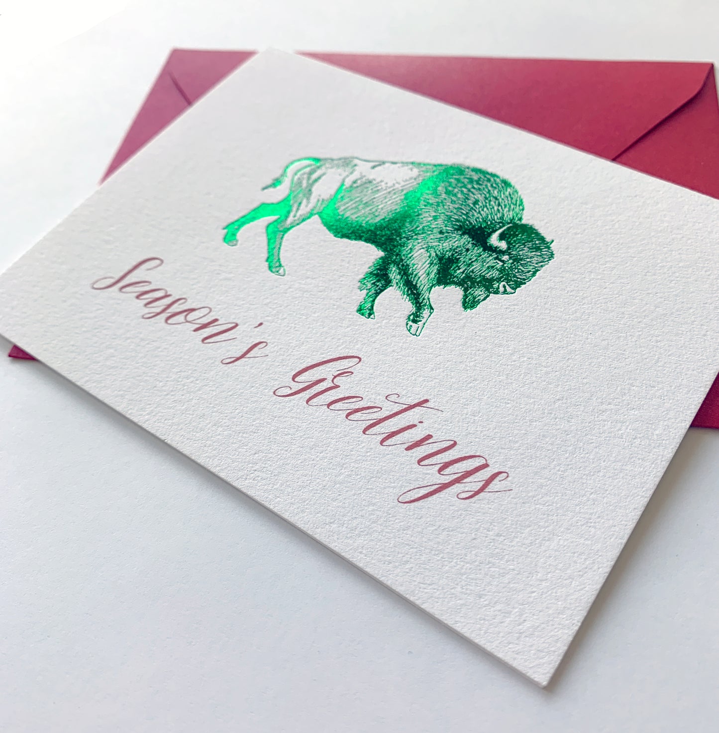 Letterpress holiday card with green foil buffalo that says "Season's greetings" by Rust Belt Love