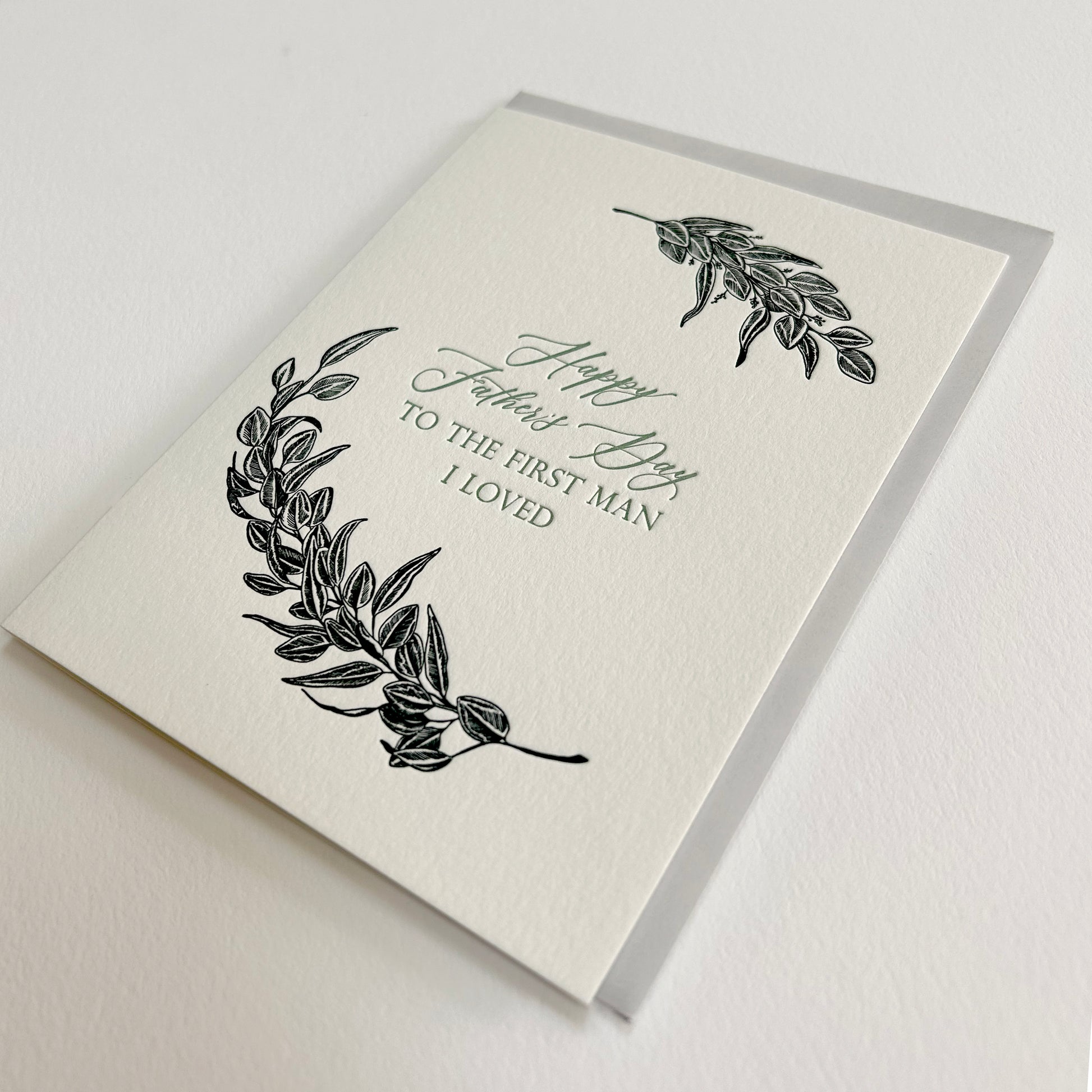 Letterpress father's day card with black greenery that reads "Happy Father's Day to the first man I loved"by Rust Belt Love