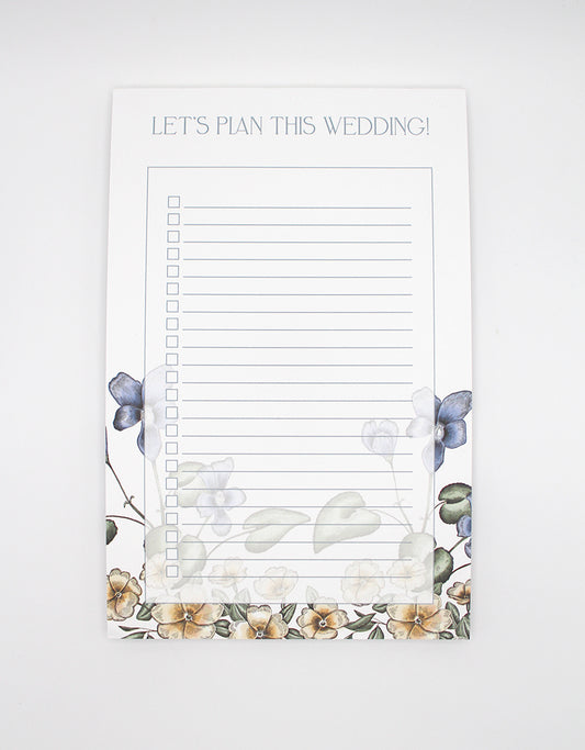 5.5 by 8.5 notepad with lined sheets with multi-colored florals that says "Let's plan this wedding!" by Rust Belt Love