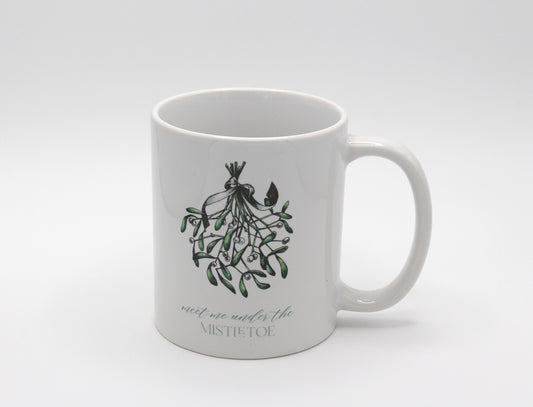 White ceramic mug with a mistletoe that says "meet me under the mistletoe by Rust Belt Love 