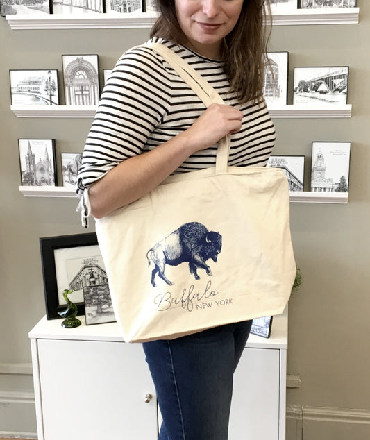 Model holding a canvas tote with a blue illustration of a buffalo that says "Buffalo New York" by Rust Belt Love