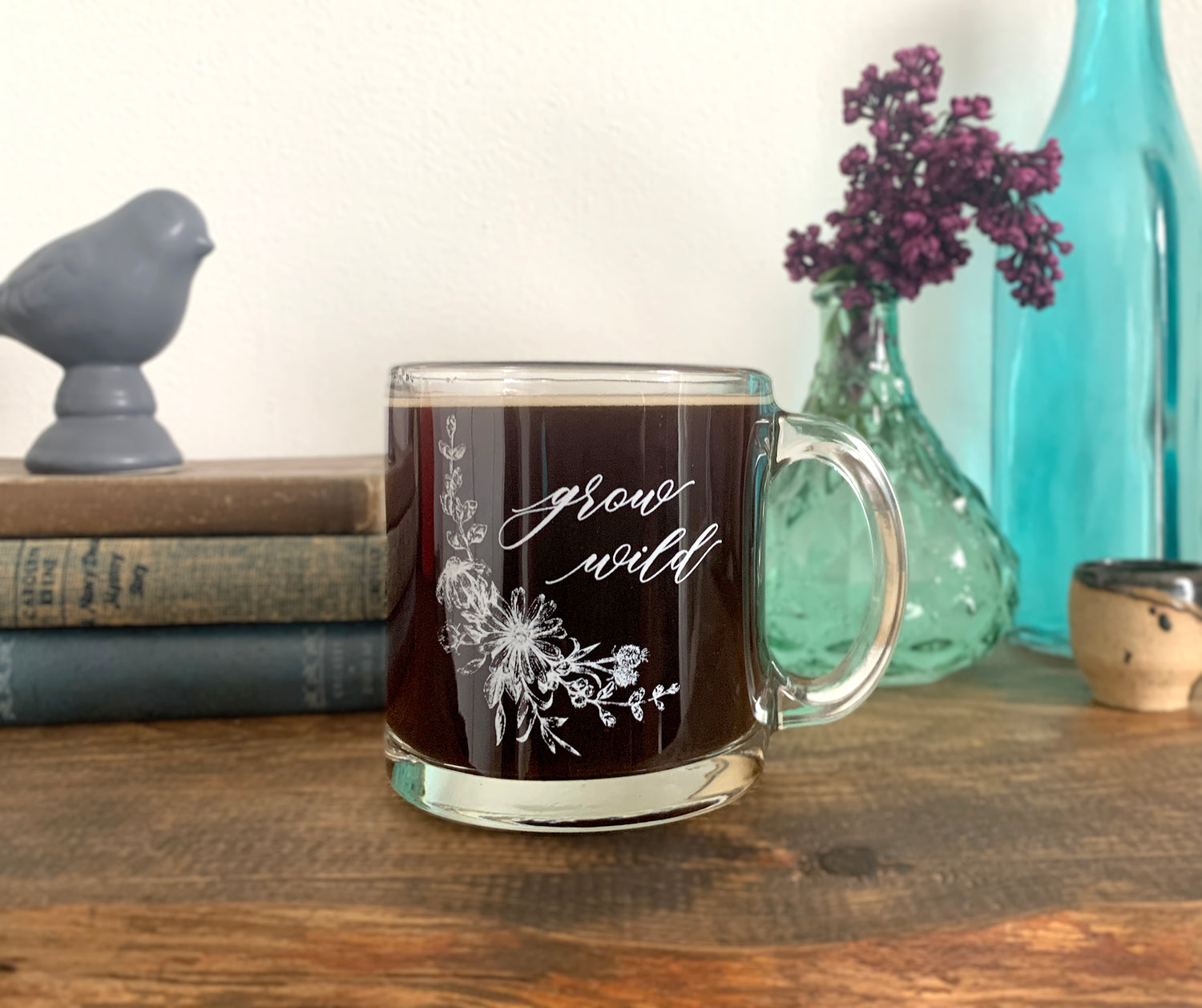White ink on clear glass mug with flowers and that says grow wild